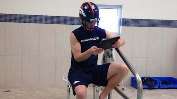 peyton manning soaking foot looking at ipad.jpg