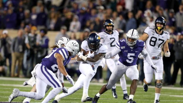 West Virginia Mountaineers running back Leddie Brown (4) is tackled by Kansas State Wildcats linebacker Da'Quan Patton (5) and defensive back Denzel Goolsby (20) during the fourth quarter of a game at Bill Snyder Family Stadium