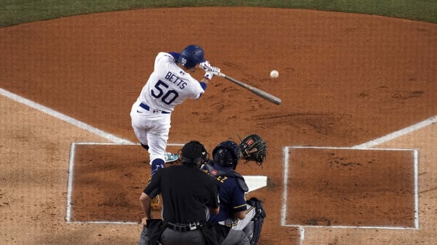 Sep 30, 2020; Los Angeles, California, USA; Los Angeles Dodgers right fielder Mookie Betts (50) follows through on a double in the first inning as Milwaukee Brewers catcher Omar Narvaez (10) and umpire Mark Ripperger (90) watch during Game 1 of the National League Wild Card Playoffs at Dodger Stadium. Mandatory Credit: Kirby Lee-USA TODAY Sports