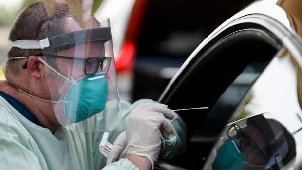 Brad Lenn, an Ascension St. Vincent respiratory therapist, prepares to collect a nasal swab sample from a person at the free, first-come, first-serve COVID-19 testing site run by the Vanderburgh County Health Department in the parking lot of an empty medical building on Covert Avenue in Evansville, Ind., Thursday afternoon, July 9, 2020. People had the option to drive-thru or walk up to receive a test.
