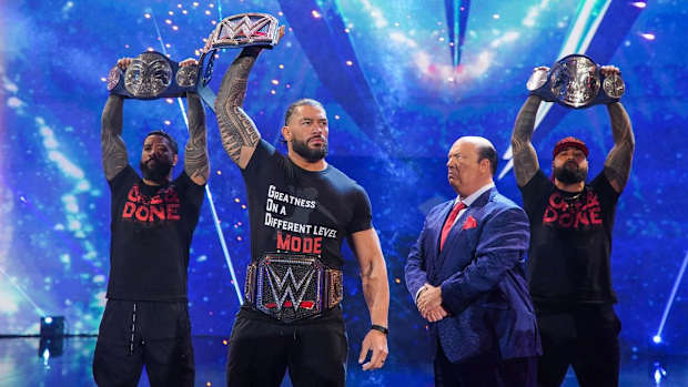 Roman Reigns poses with his championship belts on Raw