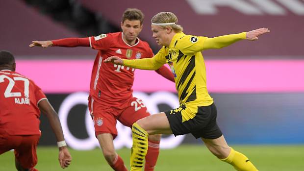 Erling Haaland dribbles past Thomas Müller.