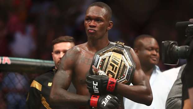 Israel Adesanya grips his UFC belt.