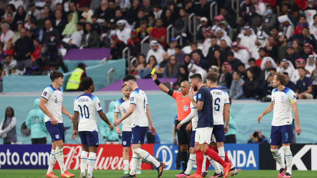 Referee Wilton Sampaio pictured showing a yellow card to Harry Maguire (left) during the 2022 World Cup quarter-final between England and France