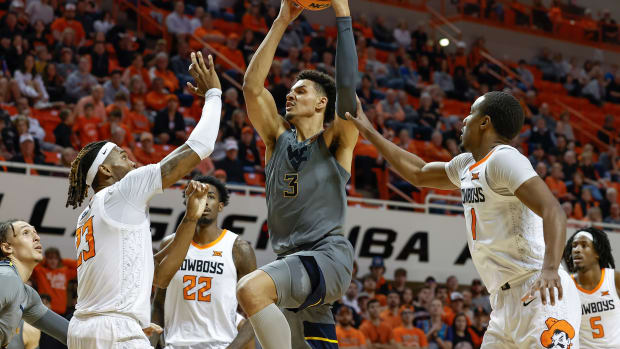 Jan 2, 2023; Stillwater, Oklahoma, USA; West Virginia Mountaineers forward Tre Mitchell (3) drives to the basket between Oklahoma State Cowboys forward Tyreek Smith (23) and guard Bryce Thompson (1) during the second half at Gallagher-Iba Arena. Oklahoma State won 67-60.