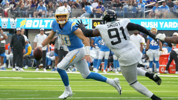Sep 25, 2022; Inglewood, California, USA; Los Angeles Chargers quarterback Justin Herbert (10) runs the ball under pressure from Jacksonville Jaguars defensive end Dawuane Smoot (91) in the third quarter at SoFi Stadium.