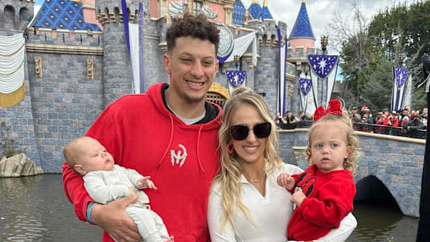 Patrick Mahomes con su esposa y dos hijas posan ante el castillo de Disneylandia.