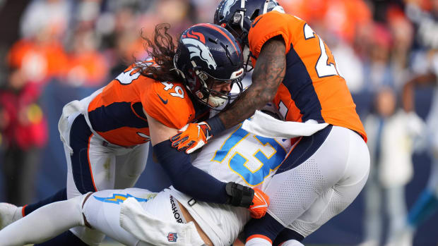 Jan 8, 2023; Denver, Colorado, USA; Denver Broncos linebacker Alex Singleton (49) and safety Kareem Jackson (22) tackle Los Angeles Chargers wide receiver Keenan Allen (13) during the first quarter at Empower Field at Mile High.