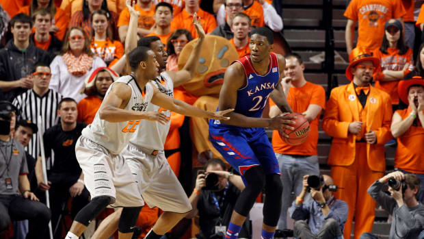 Mar 1, 2014; Stillwater, OK, USA; Kansas Jayhawks center Joel Embiid (21) is defended by Oklahoma State Cowboys forward/center Kamari Murphy (21) and guard Markel Brown (22) during the first half at Gallagher-Iba Arena