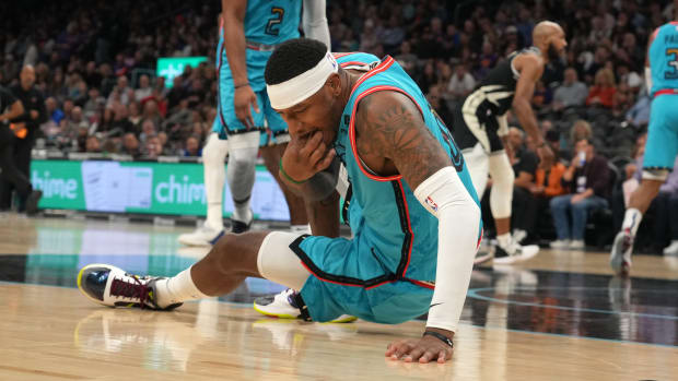 Suns forward Torrey Craig (0) retrieves his tooth from the court during the game against the Bucks.