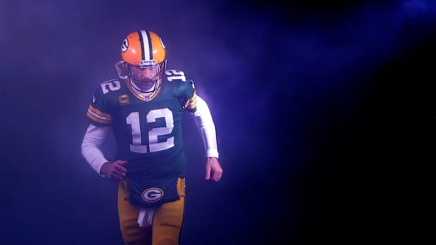 Aaron Rodgers en uniforme de Packers corre por el humo