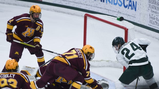 Minnesota hockey players group by the net to try to block a scorer on the other team