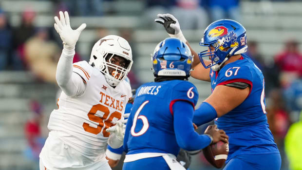 Nov 19, 2022; Lawrence, Kansas, USA; Texas Longhorns defensive lineman Moro Ojomo (98) rushes Kansas Jayhawks quarterback Jalon Daniels (6) as offensive lineman Dominick Puni (67) blocks during the second half at David Booth Kansas Memorial Stadium. Mandatory Credit: Jay Biggerstaff-USA TODAY Sports