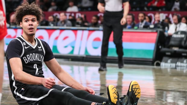 Nets forward Cameron Johnson sits on the floor after being fouled