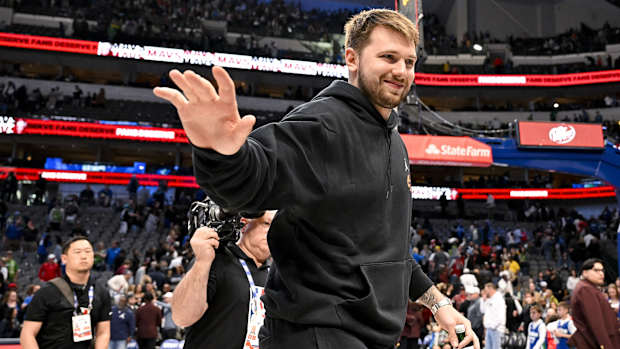 Luka Doncic saluda al público en las gradas vistiendo pants negros
