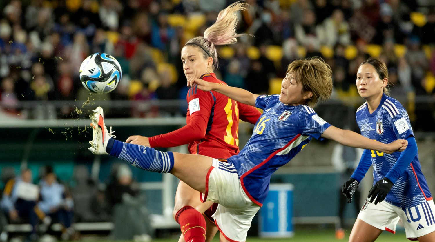 Grass flies from Japan's Honoka Hayashi's boot as she stretches to make a waist high kick behind Spain's Alexia Putellas at the Women's World Cup.