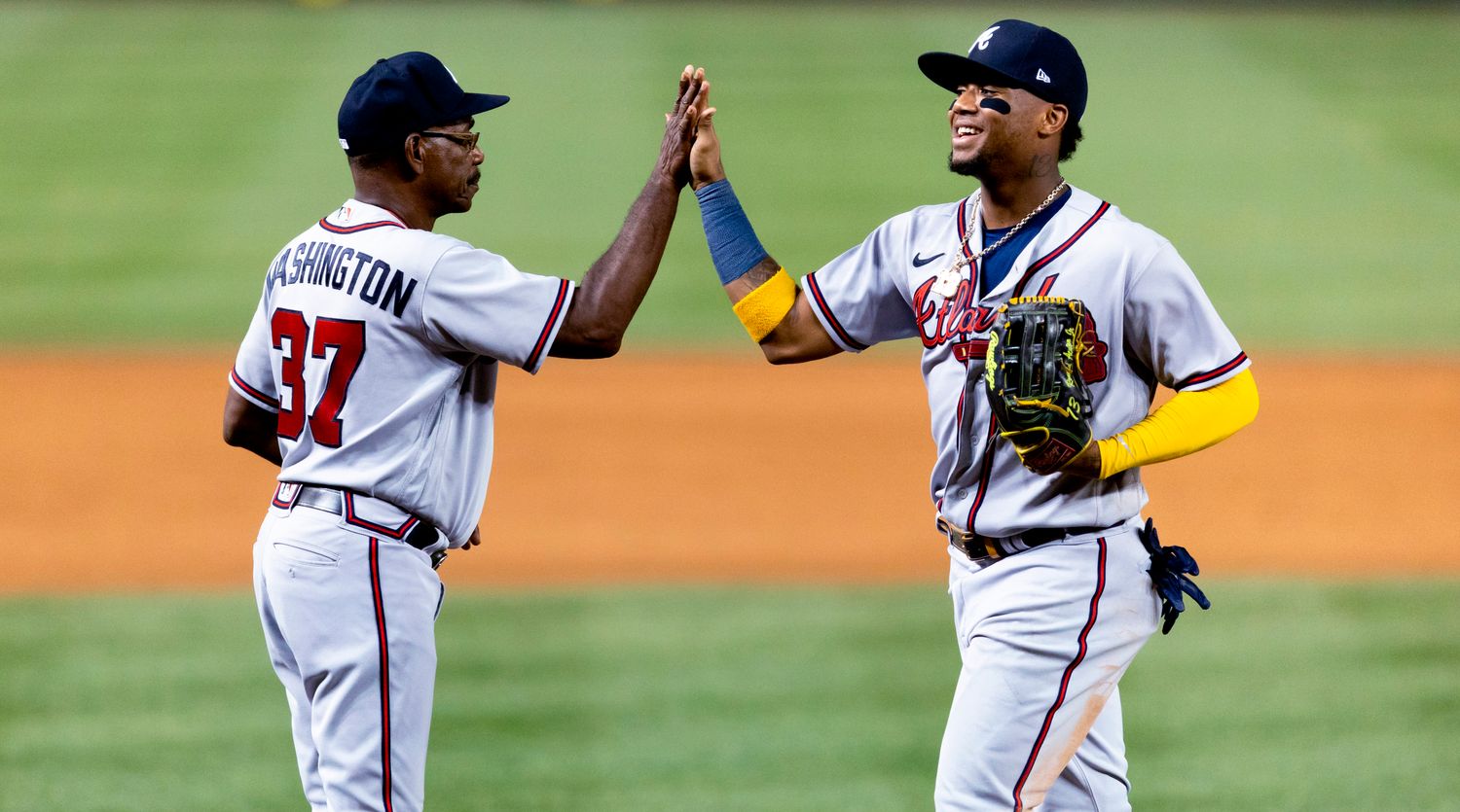 Atlanta Braves’ Ronald Acuña Jr. high-fives third base coach Ron Washington following the team’s baseball game against the Washington Nationals on Tuesday, June 14, 2022, in Washington. The Braves won 10-4.