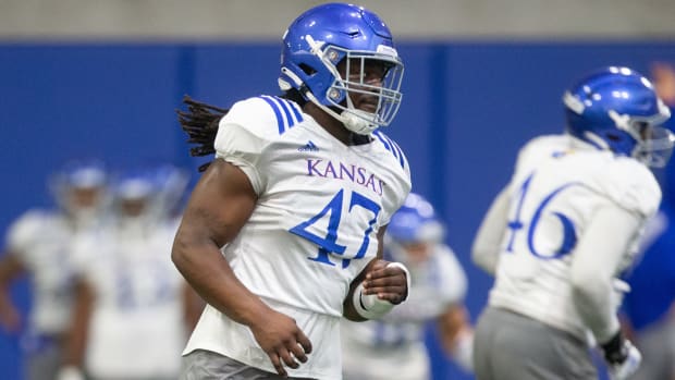 Kansas redshirt junior defensive end Lonnie Phelps (47) runs through drills during practice Friday evening at the indoor practice facility.