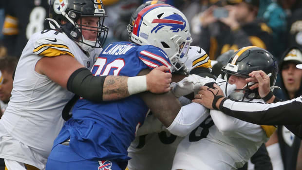 Bills defensive end Shaq Lawson (90) and Steelers quarterback Kenny Pickett grab each others face masks in a scrum.