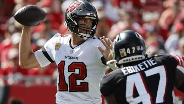 Buccaneers quarterback Tom Brady throws a pass while Falcons defensive end Arnold Ebiketie rushes him.