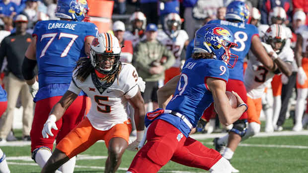 Nov 5, 2022; Lawrence, Kansas, USA; Kansas Jayhawks quarterback Jason Bean (9) runs for a touchdown as Oklahoma State Cowboys safety Kendal Daniels (5) defends during the first half of the game at David Booth Kansas Memorial Stadium. Mandatory Credit: Denny Medley-USA TODAY Sports