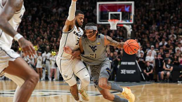 Jan 23, 2024; Orlando, Florida, USA; West Virginia Mountaineers guard RaeQuan Battle (21) drives to the basket around UCF Knights guard Darius Johnson (3) during the first half at Addition Financial Arena. Mandatory Credit: Mike Watters-USA TODAY Sports