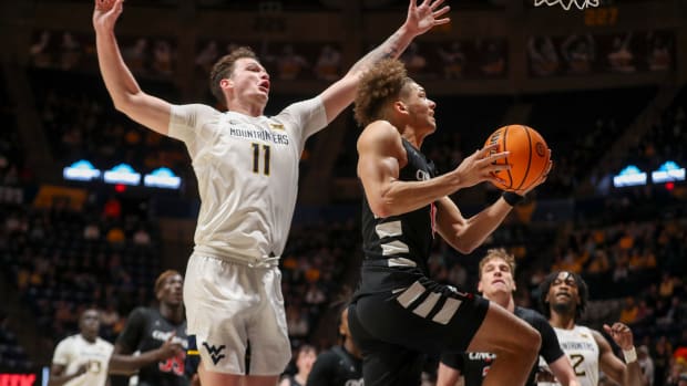 Jan 31, 2024; Morgantown, West Virginia, USA; Cincinnati Bearcats guard Dan Skillings Jr. (0) drives and shoots against West Virginia Mountaineers forward Quinn Slazinski (11) during the first half at WVU Coliseum. Mandatory Credit: Ben Queen-USA TODAY Sports