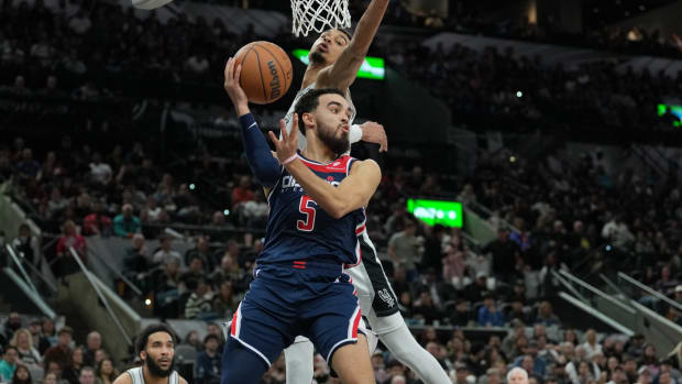 Jan 29, 2024; San Antonio, Texas, USA; Washington Wizards guard Tyus Jones (5) looks to pass under the arm of San Antonio Spurs center Victor Wembanyama (1) in the second half at Frost Bank Center.