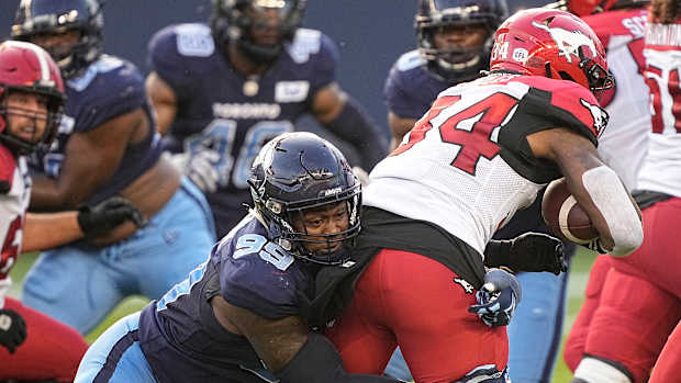 Aug 20, 2022; Toronto, Ontario, CAN; Toronto Argonauts defensive lineman Dewayne Hendrix (99) tackles Calgary Stampeders running back Dedrick Mills (34) at BMO Field. Mandatory Credit: John E. Sokolowski-USA TODAY Sports  