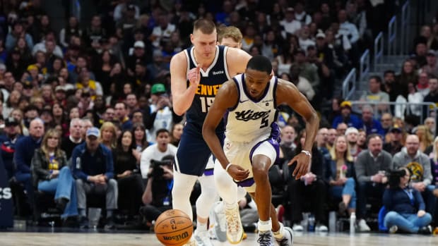 Feb 14, 2024; Denver, Colorado, USA; Sacramento Kings guard De'Aaron Fox (5) chases down a loose ball away from Denver Nuggets center Nikola Jokic (15) in the fourth quarter at Ball Arena. Mandatory Credit: Ron Chenoy-USA TODAY Sports  