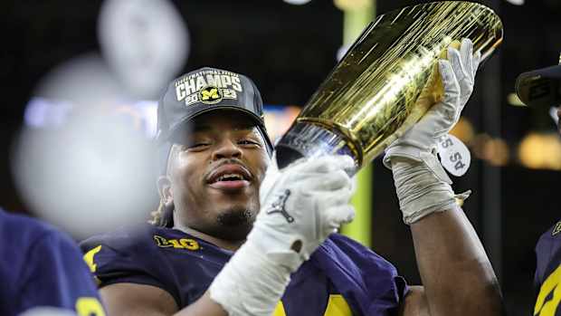 Michigan defensive lineman Kris Jenkins (94) picks up the trophy to celebrate the Wolverines' 34-13 win over Washington at the national championship game at NRG Stadium in Houston on Monday, Jan. 8, 2024.