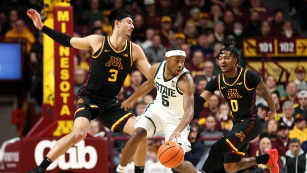 Feb 6, 2024; Minneapolis, Minnesota, USA; Michigan State Spartans guard Tre Holloman (5) dribbles as Minnesota Golden Gophers forward Dawson Garcia (3) and guard Elijah Hawkins (0) defend during the first half at Williams Arena.