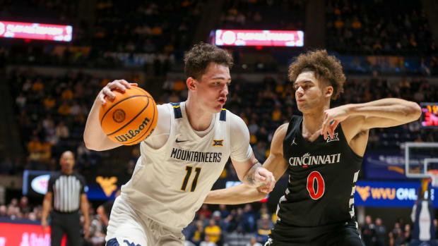 Jan 31, 2024; Morgantown, West Virginia, USA; West Virginia Mountaineers forward Quinn Slazinski (11) drives baseline against Cincinnati Bearcats guard Dan Skillings Jr. (0) during the second half at WVU Coliseum. Mandatory Credit: Ben Queen-USA TODAY Sports