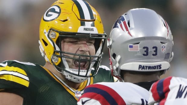 Aug 19, 2023; Green Bay, WI, USA; Green Bay Packers guard Jon Runyan (76) and New England Patriots linebacker Anfernee Jennings (33) exchange words following a play during their preseason football game at Lambeau Field. The game was suspended in the fourth quarter following an injury to New England Patriots cornerback Isaiah Bolden (7).