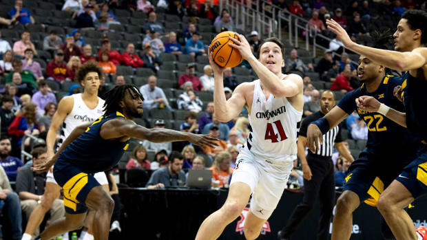 Cincinnati Bearcats guard Simas Lukosius (41) drives to the basket between West Virginia Mountaineers defenders in the first half of the Big 12 Conference tournament between Cincinnati Bearcats and West Virginia Mountaineers at T-Mobile Center in Kansas City, Mo., on Tuesday, March 12, 2024.