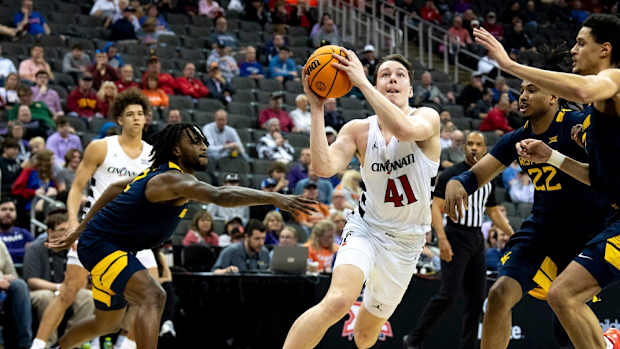 Cincinnati Bearcats guard Simas Lukosius (41) drives to the basket between West Virginia Mountaineers defenders in the first half of the Big 12 Conference tournament between Cincinnati Bearcats and West Virginia Mountaineers at T-Mobile Center in Kansas City, Mo., on Tuesday, March 12, 2024.