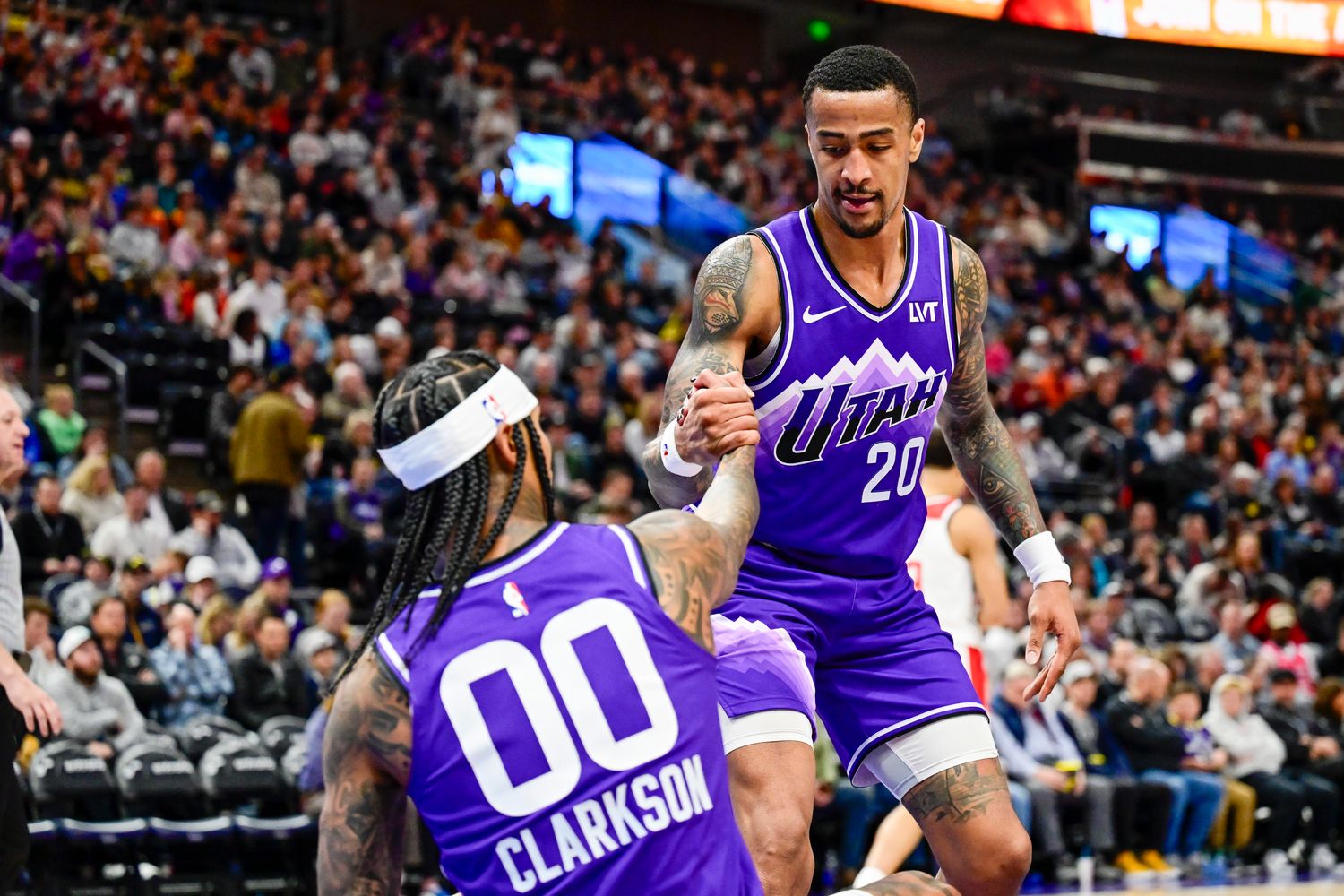 Mar 4, 2024; Salt Lake City, Utah, USA; Utah Jazz forward/center John Collins (20) helps guard Jordan Clarkson (00) off the ground against the Washington Wizards during the second half at the Delta Center. Mandatory Credit: Christopher Creveling-USA TODAY Sports
