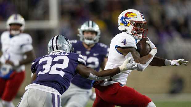 Kansas sophomore running back Devin Neal (4) runs through Kansas State redshirt freshman linebacker Desmond Purnell (32) during the first quarter of Saturday's Sunflower Showdown game at Bill Snyder Family Stadium.  