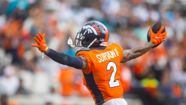 Pat Surtain II puts his hands out to the side holding the football in one hand
