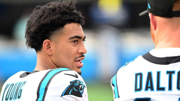 Bryce Young turns his head to the side to talk to Andy Dalton standing next to him