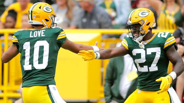 Green Bay packers QB jordan love puts his hand out to meet Patrick Taylor’s hand in celebration