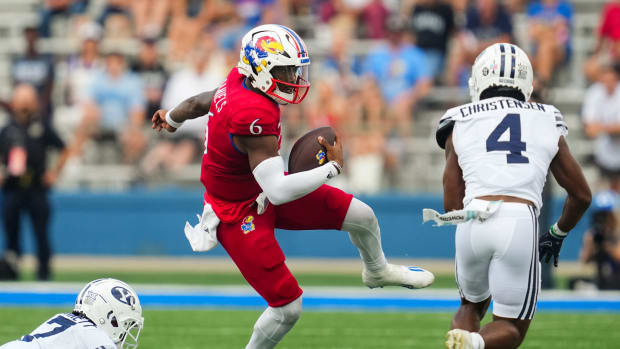 Sep 23, 2023; Lawrence, Kansas, USA; Kansas Jayhawks quarterback Jalon Daniels (6) runs the ball against Brigham Young Cougars cornerback Kamden Garrett (7) and cornerback Caleb Christensen (4) during the second half at David Booth Kansas Memorial Stadium. Mandatory Credit: Jay Biggerstaff-USA TODAY Sports  