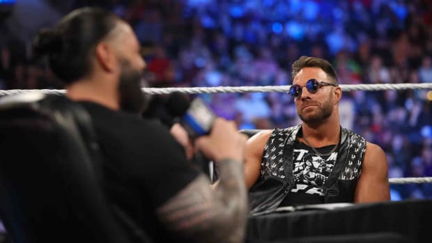 Roman Reigns and LA Knight sit at a table during a promo segment