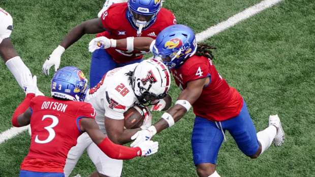 Nov 11, 2023; Lawrence, Kansas, USA; Kansas Jayhawks cornerback Mello Dotson (3) and safety Marvin Grant (4) tackle Texas Tech Red Raiders running back Tahj Brooks (28) during the first half at David Booth Kansas Memorial Stadium.