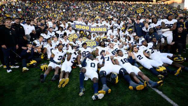 Michigan football players pose for photographers after winning the 1,000th game in program history.