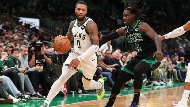 Milwaukee Bucks guard Damian Lillard drives to the basket defended by Boston Celtics guard Jrue Holiday.
