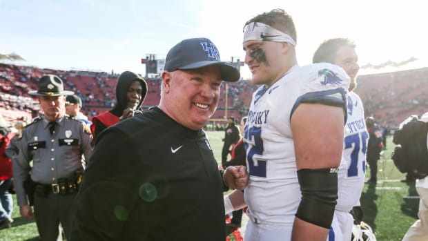 Kentucky Wildcats head coach Mark Stoops smiles with Kentucky Wildcats offensive lineman Jager Burton (62) after the Wildcats beat Louisville 38-31 Saturday. Nov. 24, 2023 