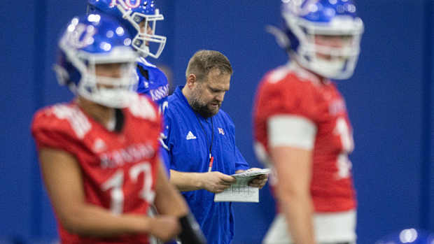 Kansas offensive coordinator Andy Kotelnicki checks his playbook during practice Tuesday in Lawrence.  