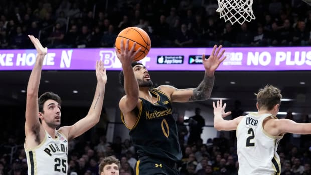 Northwestern point guard Boo Buie drives to the basket for a layup between two Purdue defenders.
