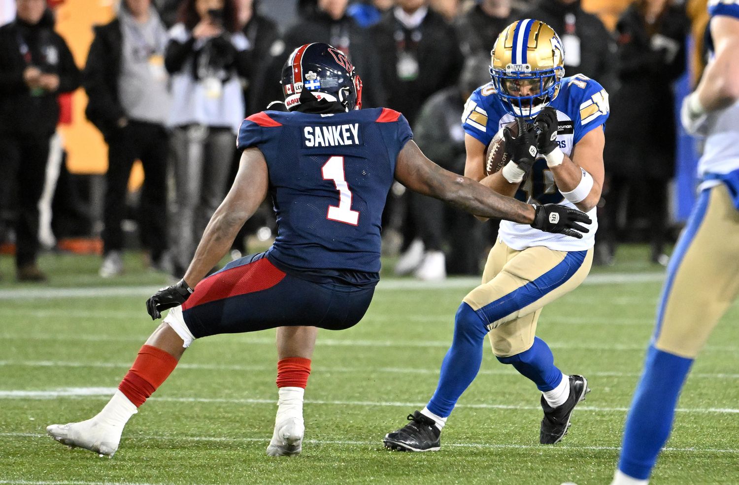 Nov 19, 2023; Hamilton, Ontario, CAN; Winnipeg Blue Bombers wide receiver Nic Demski (10) tries to elude a tackle from Montreal Alouettes defensive back Darnell Sankey (1) in the second half at Tim Hortons Field. Mandatory Credit: Dan Hamilton-USA TODAY Sports